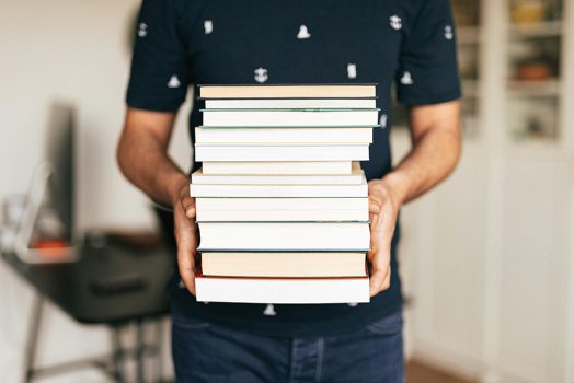 A person holding a stack of books