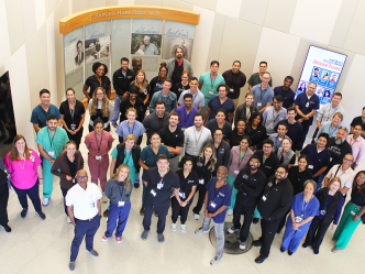 A large group of pulmonologists and pulmonology fellows pose for a photo in a medical school lobby.