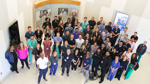 A large group of pulmonologists and pulmonology fellows pose for a photo in a medical school lobby.