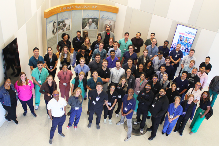 A large group of pulmonologists and pulmonology fellows pose for a photo in a medical school lobby.