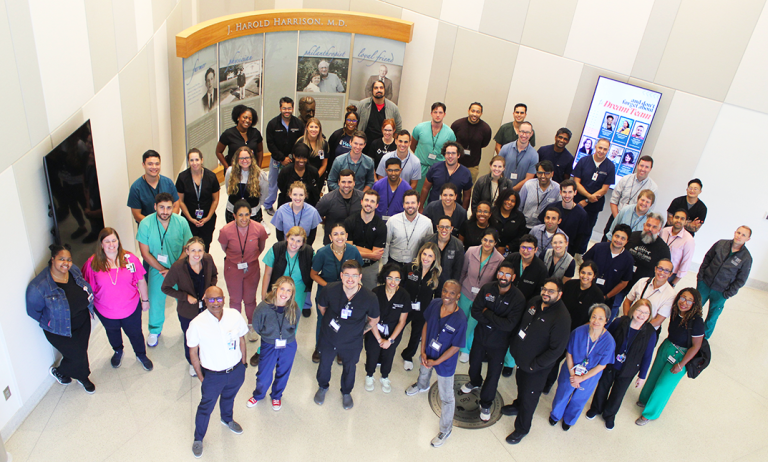 A large group of pulmonologists and pulmonology fellows pose for a photo in a medical school lobby.