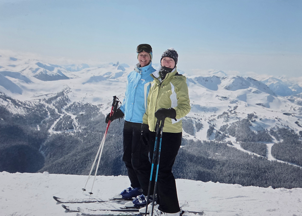 Two women skiing on top of a snowy mountain.