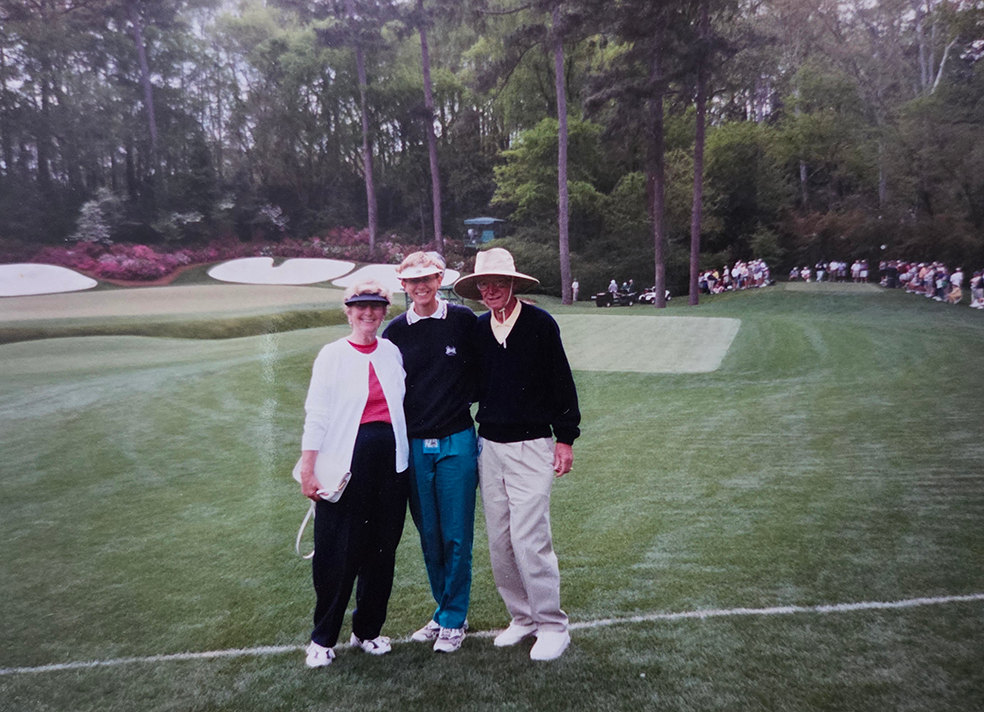 Two women and one man take a photo at a golf tournament.