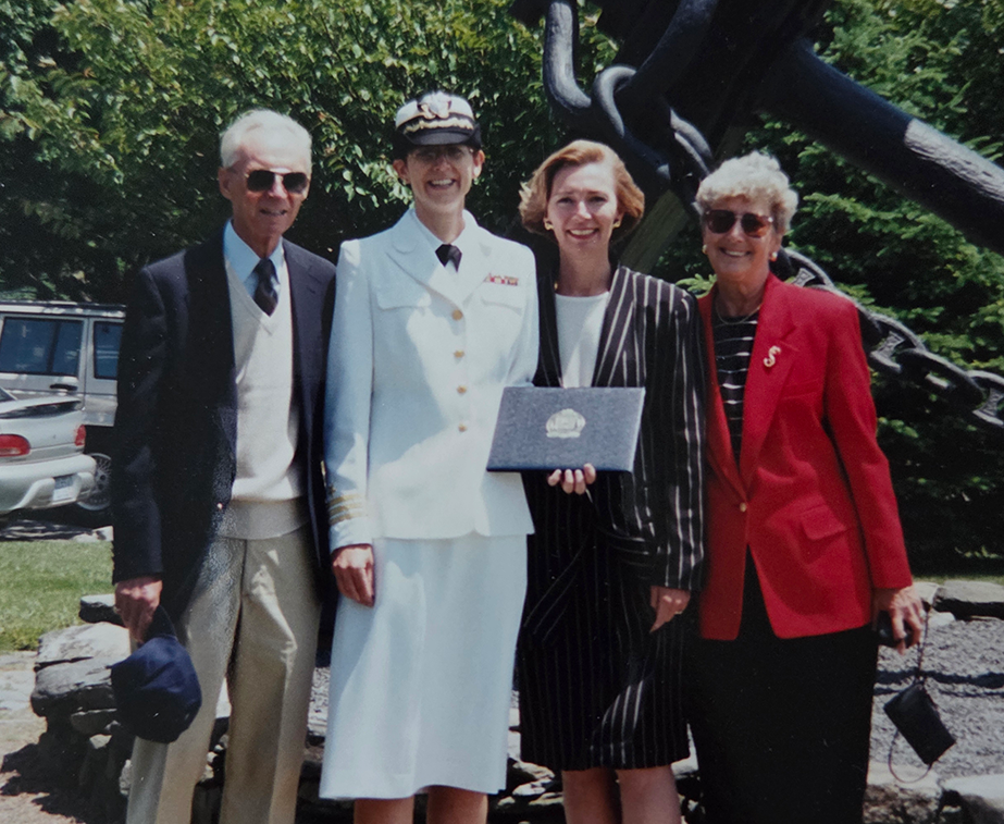 A woman wearing a U.S. Navy uniform poses with her parents and sister at a graduation ceremony for a master's program at the U.S. Naval War College.
