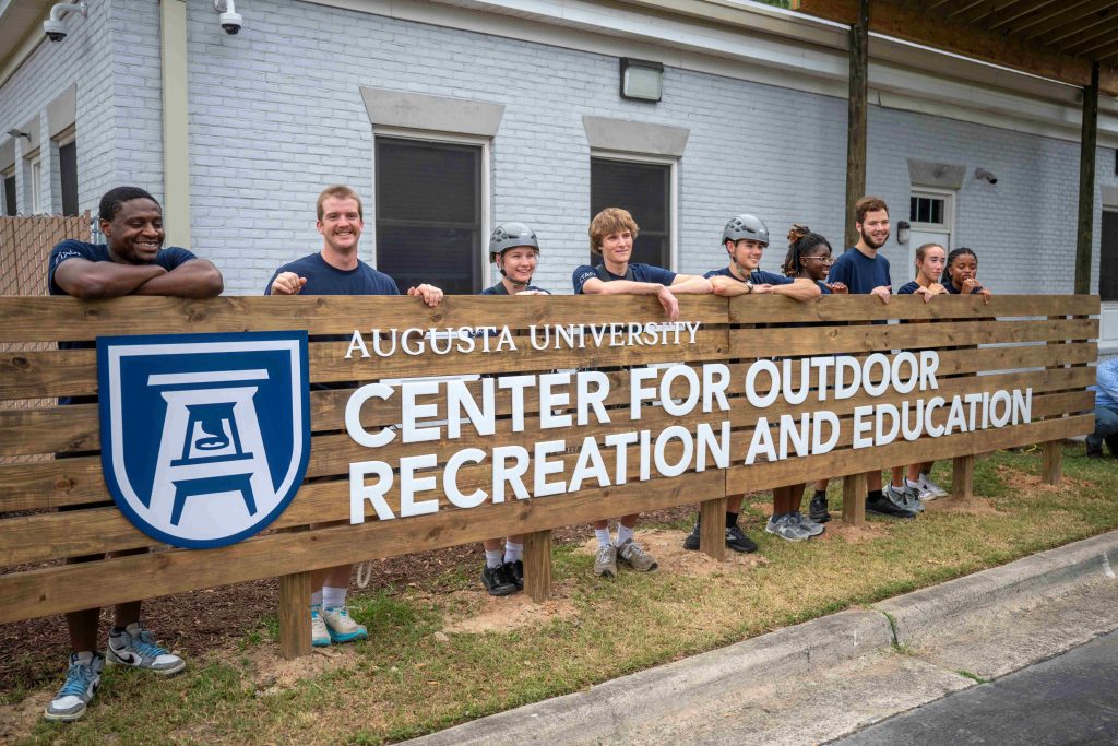 Students stand gathered around a building sign.