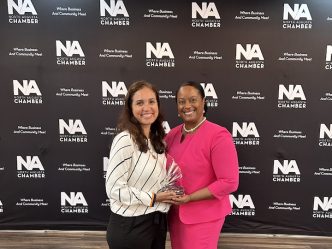 Two women pose for a picture holding an award