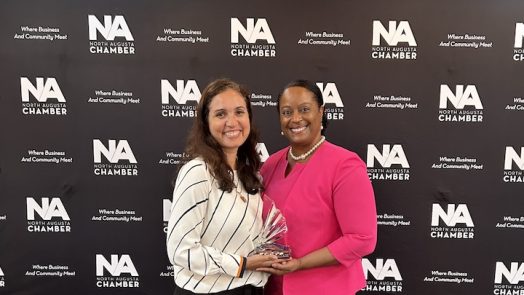 Two women pose for a picture holding an award