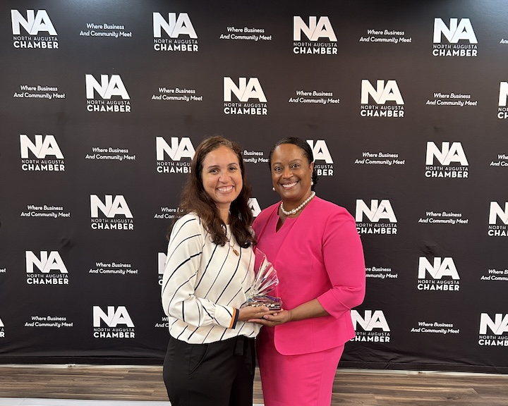 Two women pose for a picture holding an award