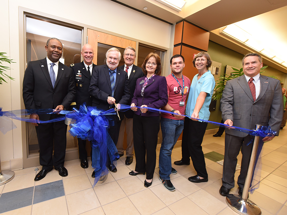 A group of university faculty cutting a ribbon to celebrate opening a new space inside a classroom building.