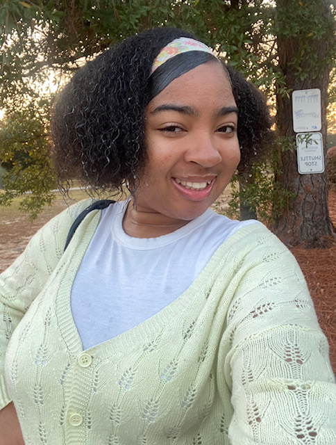A college-aged female student poses for a photo outdoors.