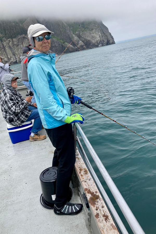 A woman wearing cold weather fishes off a pier in Alaska.
