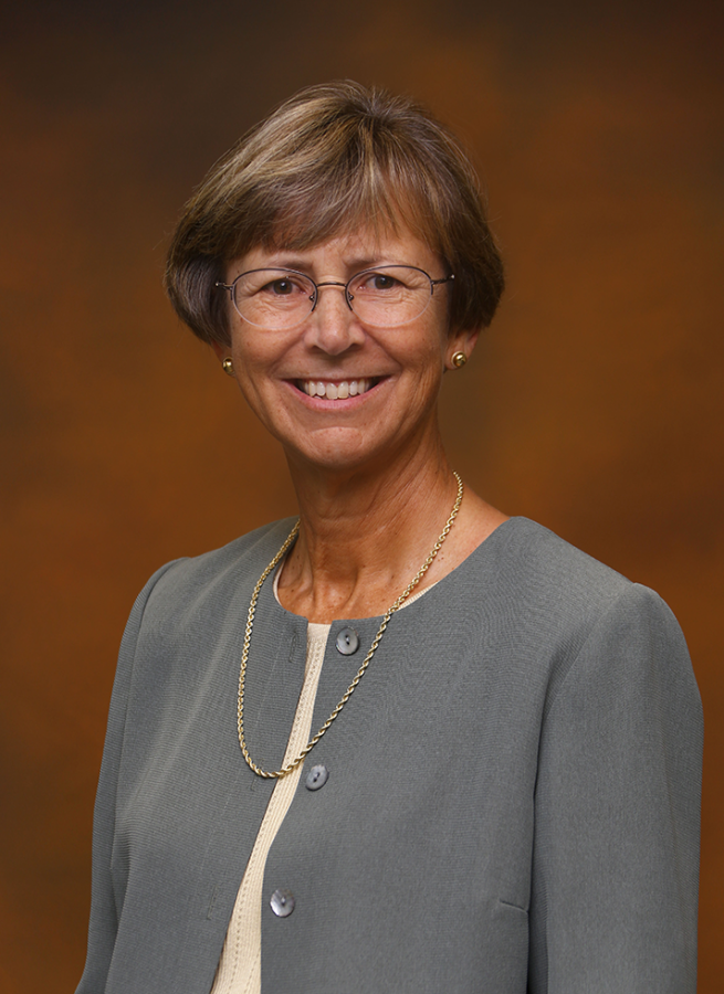 A professionally dressed female college faculty member poses for a headshot.