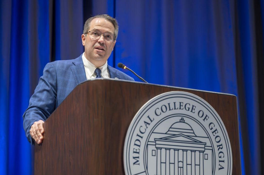 A man standing at a podium speaking to a large group of people.