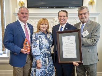 group of four stand with award and framed document