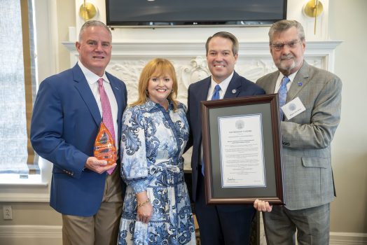 group of four stand with award and framed document