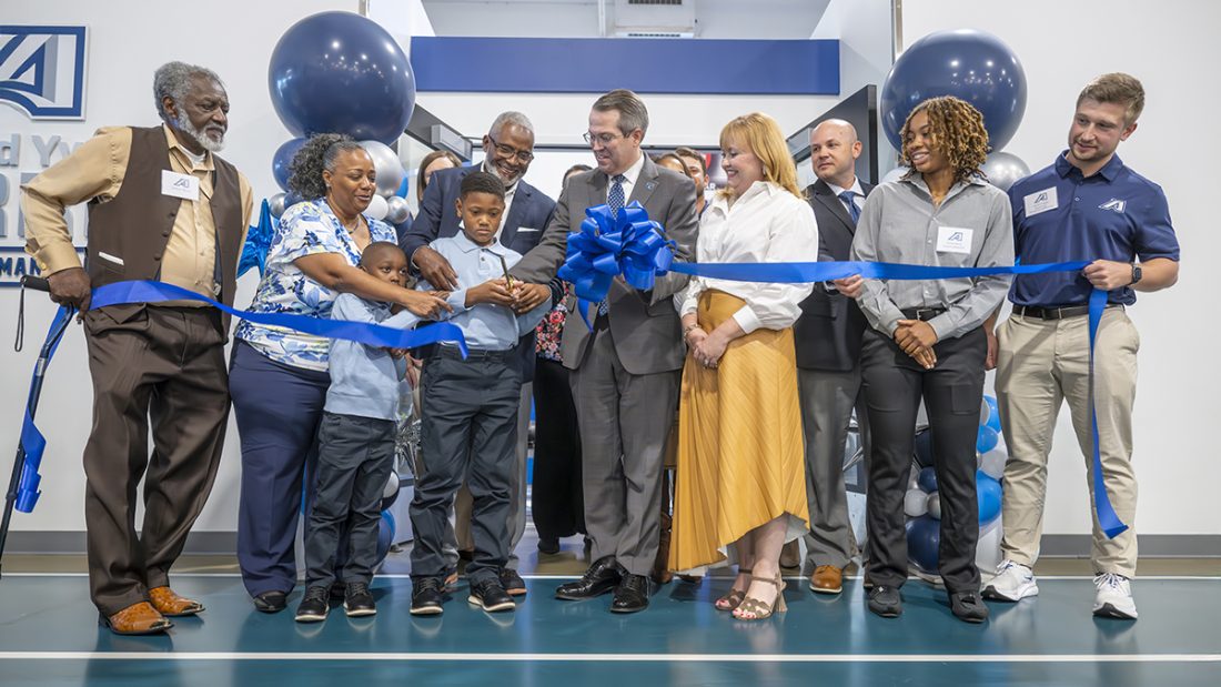 A group of people celebrate a ribbon-cutting of a brand new sports performance center.
