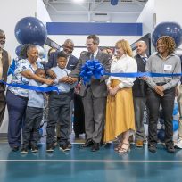 A group of people celebrate a ribbon-cutting of a brand new sports performance center.