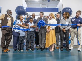A group of people celebrate a ribbon-cutting of a brand new sports performance center.