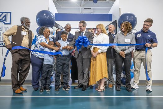 A group of people celebrate a ribbon-cutting of a brand new sports performance center.