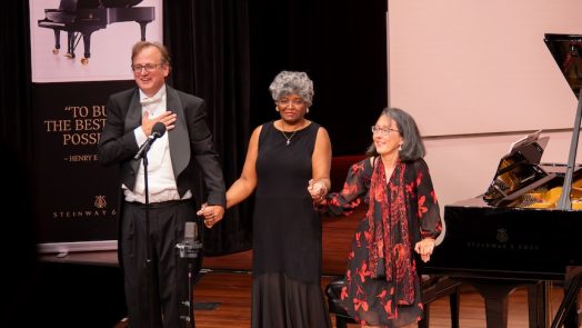 People on stage holding hands for a celebration