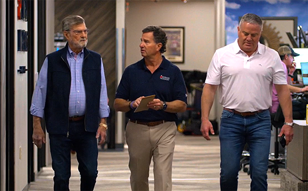 Three men walking down the hall of an office building.