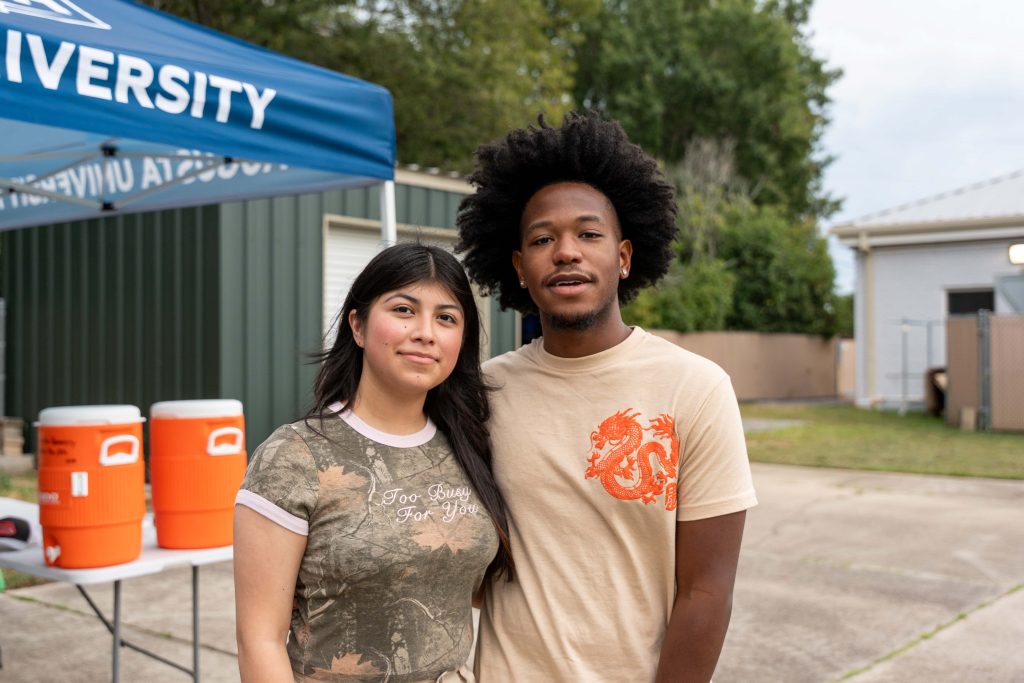 A woman and man pose for a photo while outside.