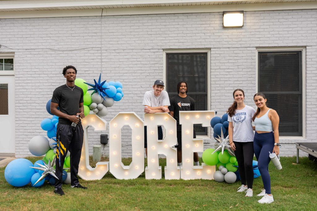Students stand gathered around a building sign.