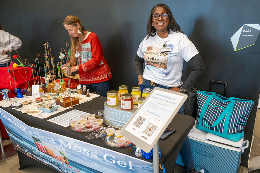 Two women man a booth during a small-business market.