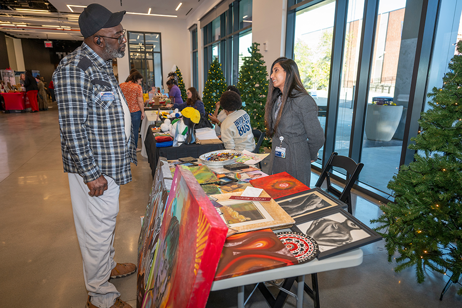 A man speaks with a woman who is selling art during a small business market.