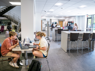 College students sit at tables in a market that is part of a college library.