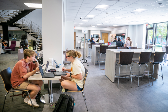 College students sit at tables in a market that is part of a college library.