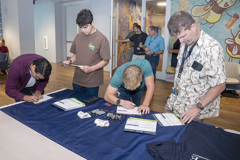 Multiple men fill out forms at table