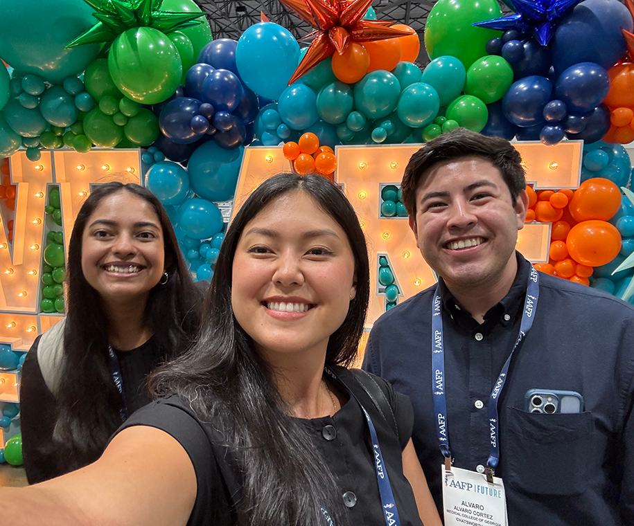 Two female medical students and one male medical student take a selfie at a national student conference.