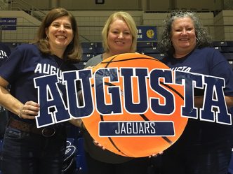 Three women holding a sign and smiling