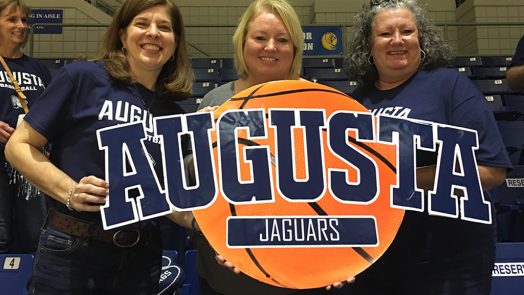 Three women holding a sign and smiling