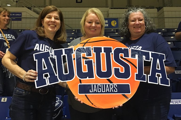Three women holding a sign and smiling