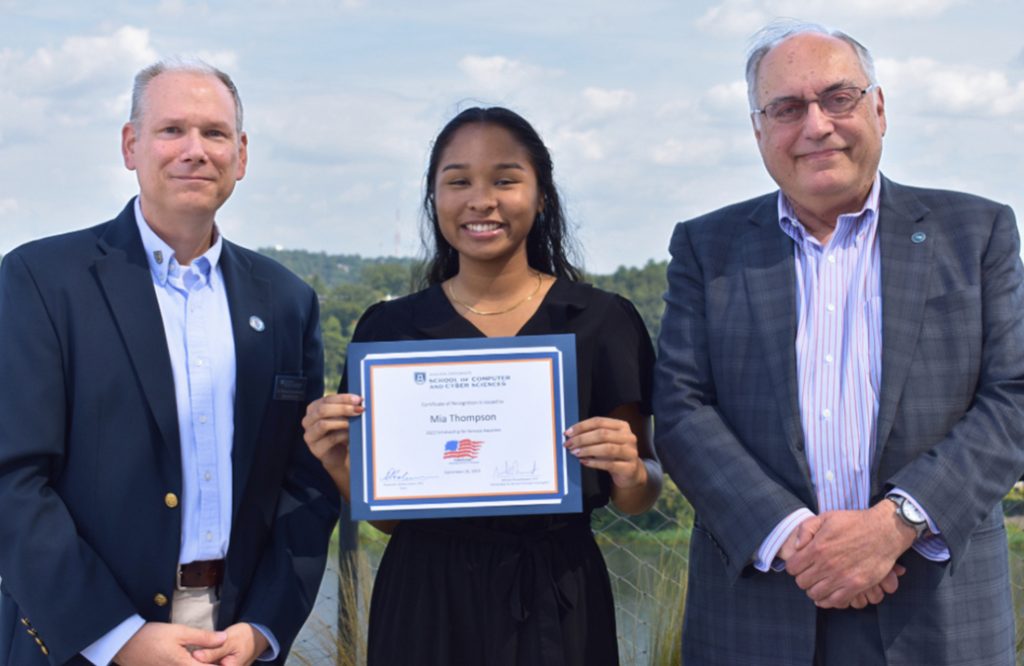 Woman holding a certificate while standing next to two men