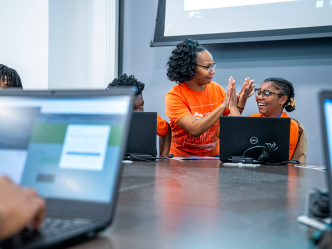 A woman and a high school girl give each other high fives during a competition.