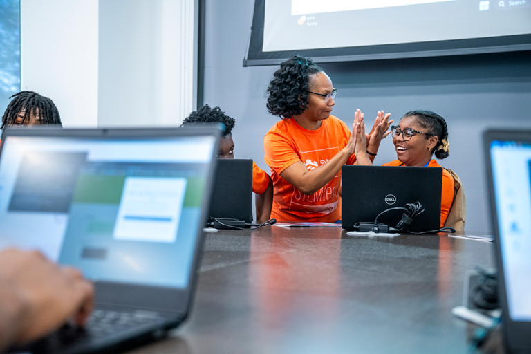 A woman and a high school girl give each other high fives during a competition.