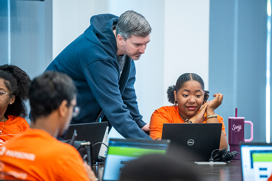 A man helps a high school girl with a computer problem during a competition.