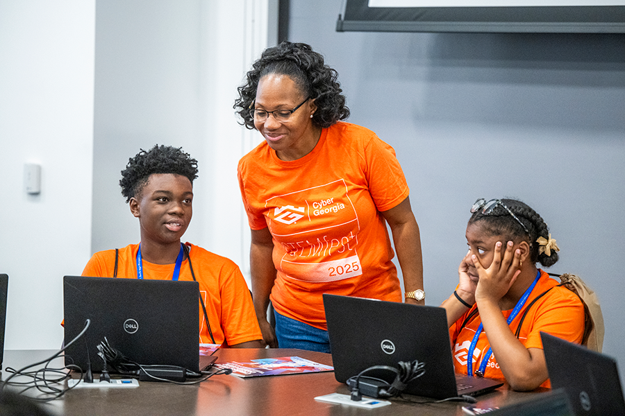 A woman looks over a male high school student's work on a laptop computer during a competition.