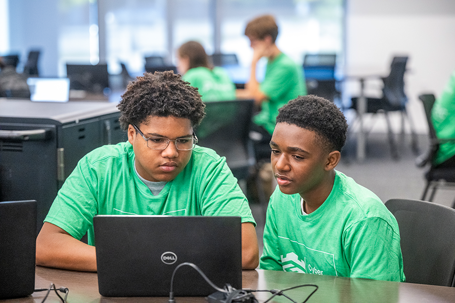 Two high school boys work on a laptop computer during a competition.