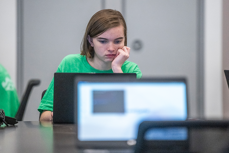 A high school girl works on a laptop computer.