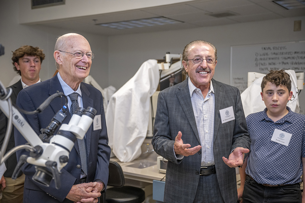 Two men stand with equipment and two teen men look on