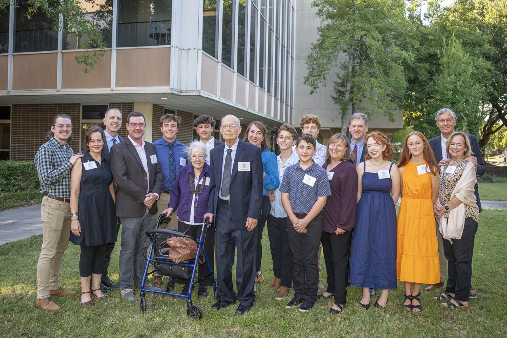 group of about 18 stand together outside for a photo