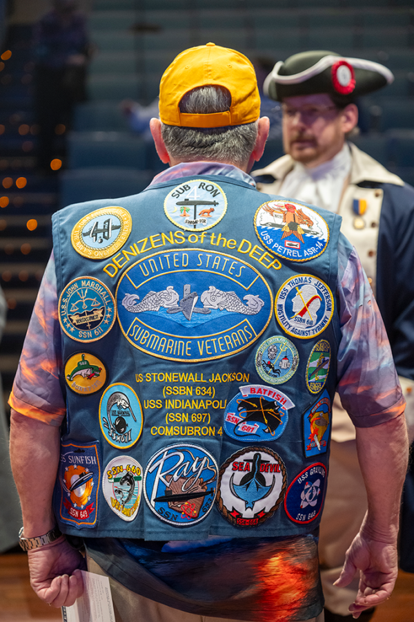 The back of a man wearing a vest covered in patches.