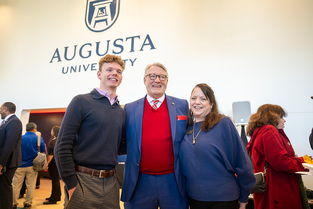 Two men and a woman pose with linked arms.