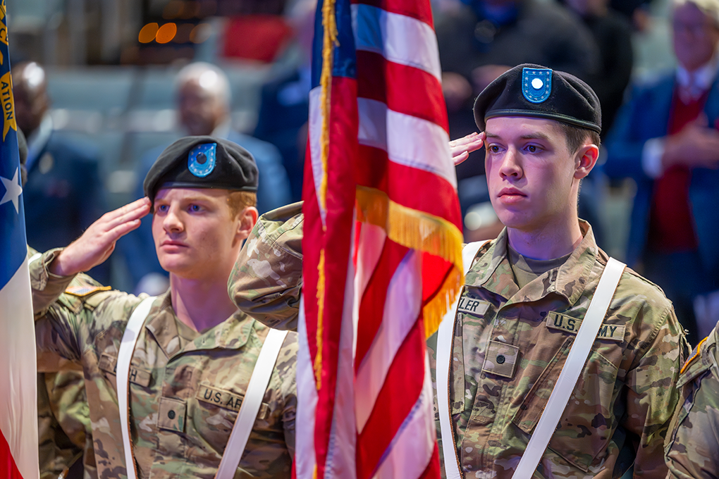 Two young men in fatigues salute the flag.