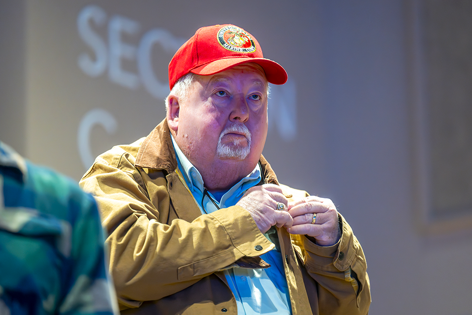 A man in a red hat places a pin on his jacket.