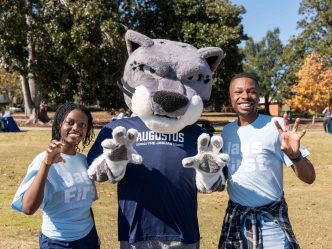 Augusta University mascot, Augustus, with two female students.